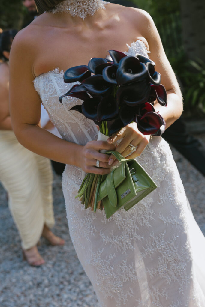 Bride holding black calla lily bouquet in a strapless lace gown.
