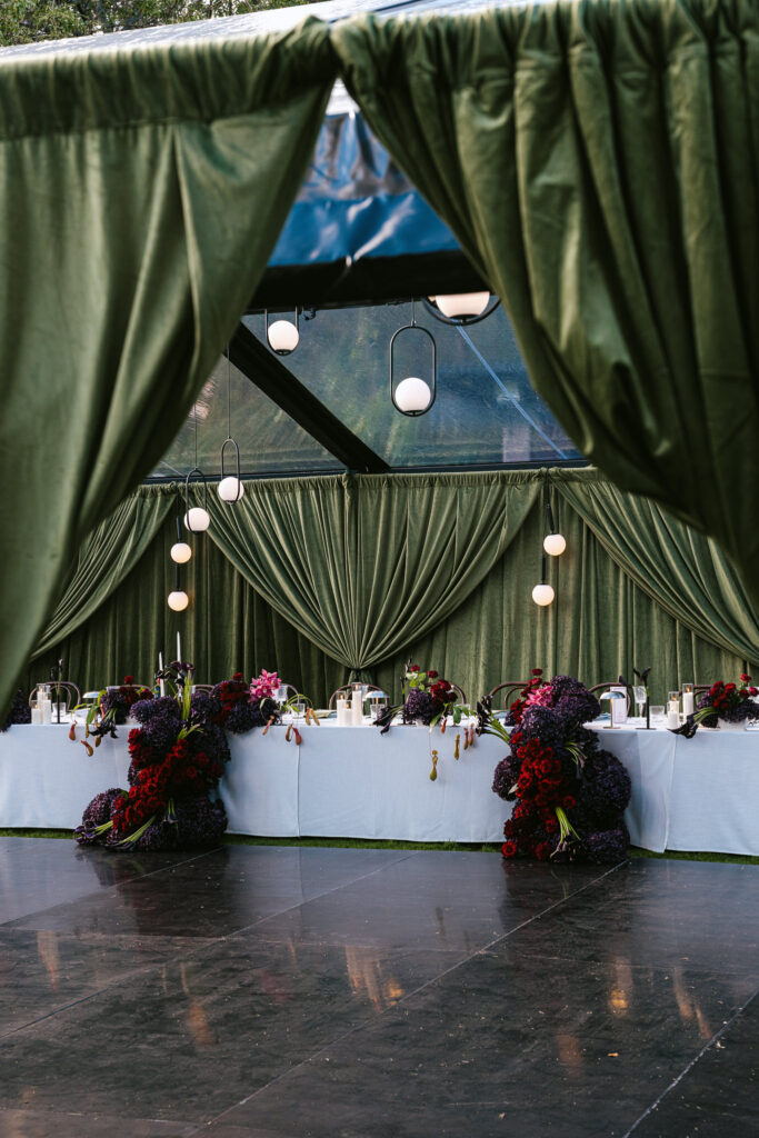 A marquee wedding reception at Whites Valley Estate with dark green draping and warm pendant lighting.