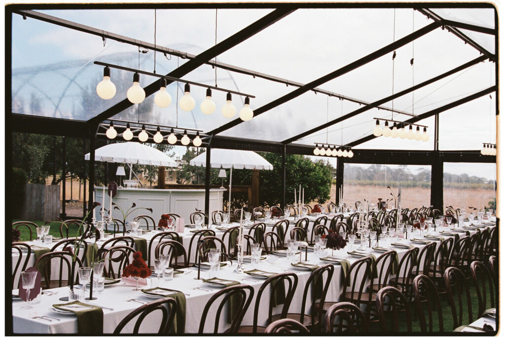 Clear marquee reception setup at Whites Valley Estate with pendant globe lights and vineyard views.