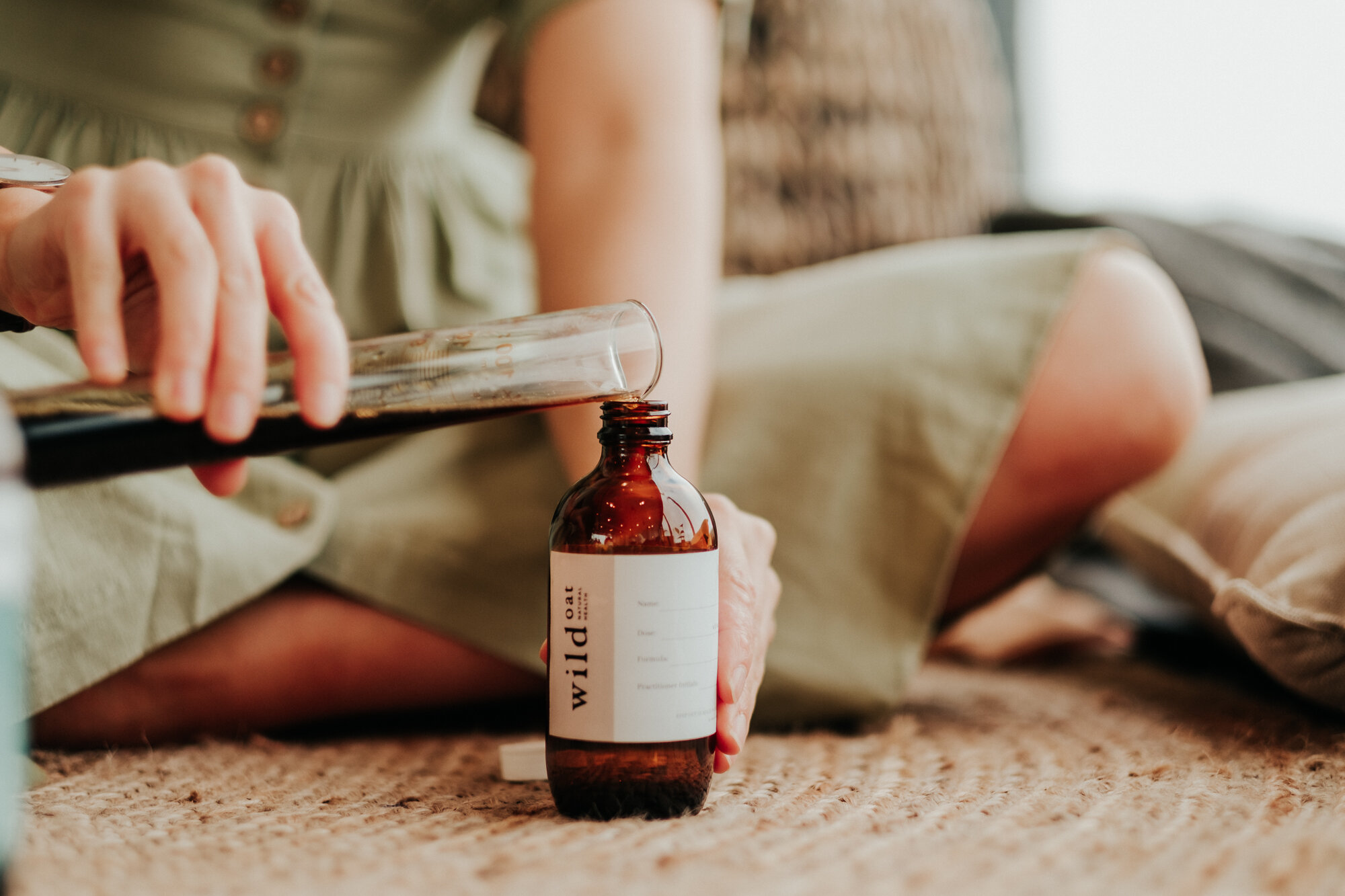 a naturopath pours a herbal tincture into a brown glass bottle