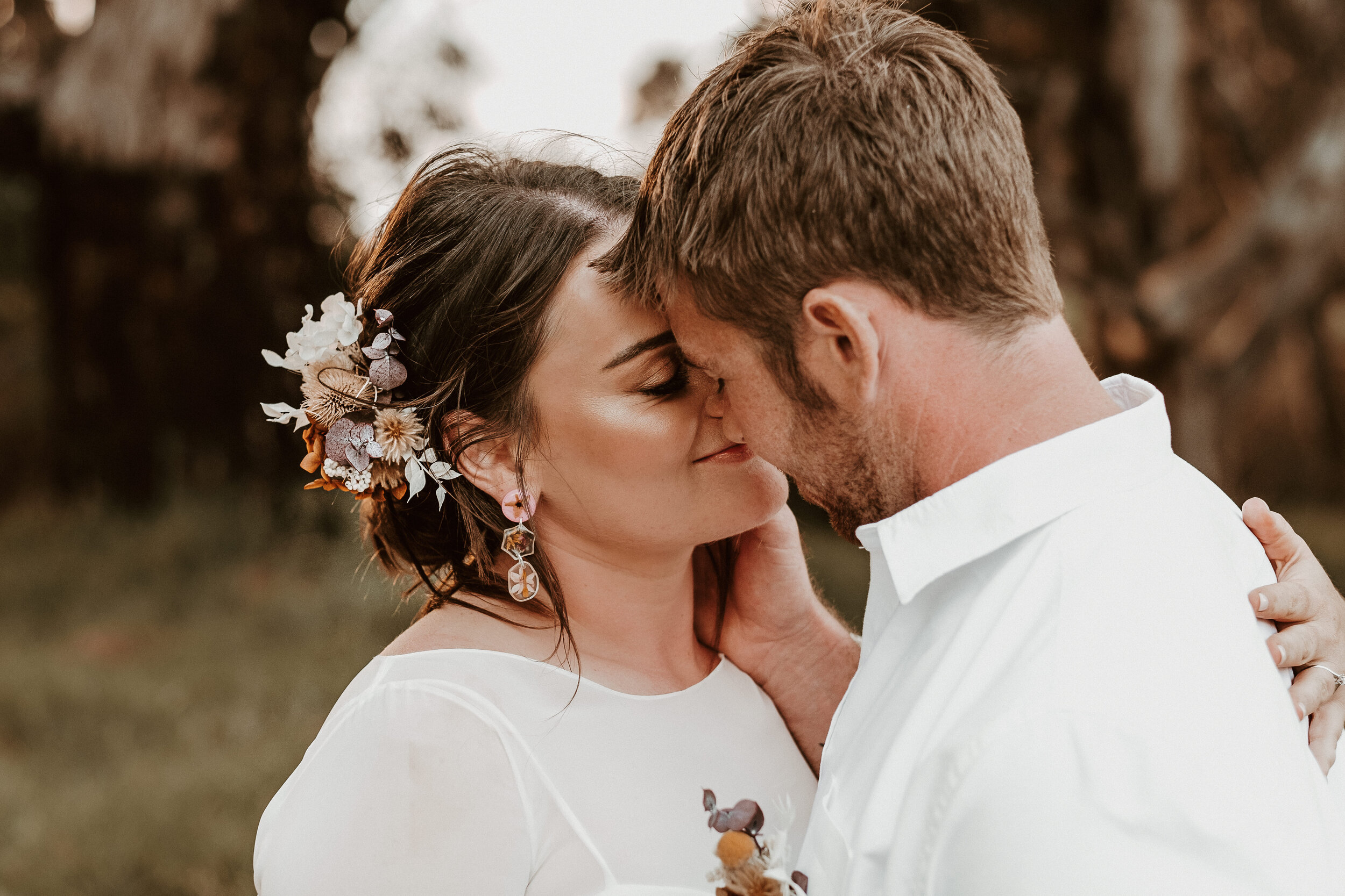 a bride and groom touch noses, smiling with their eyes closed