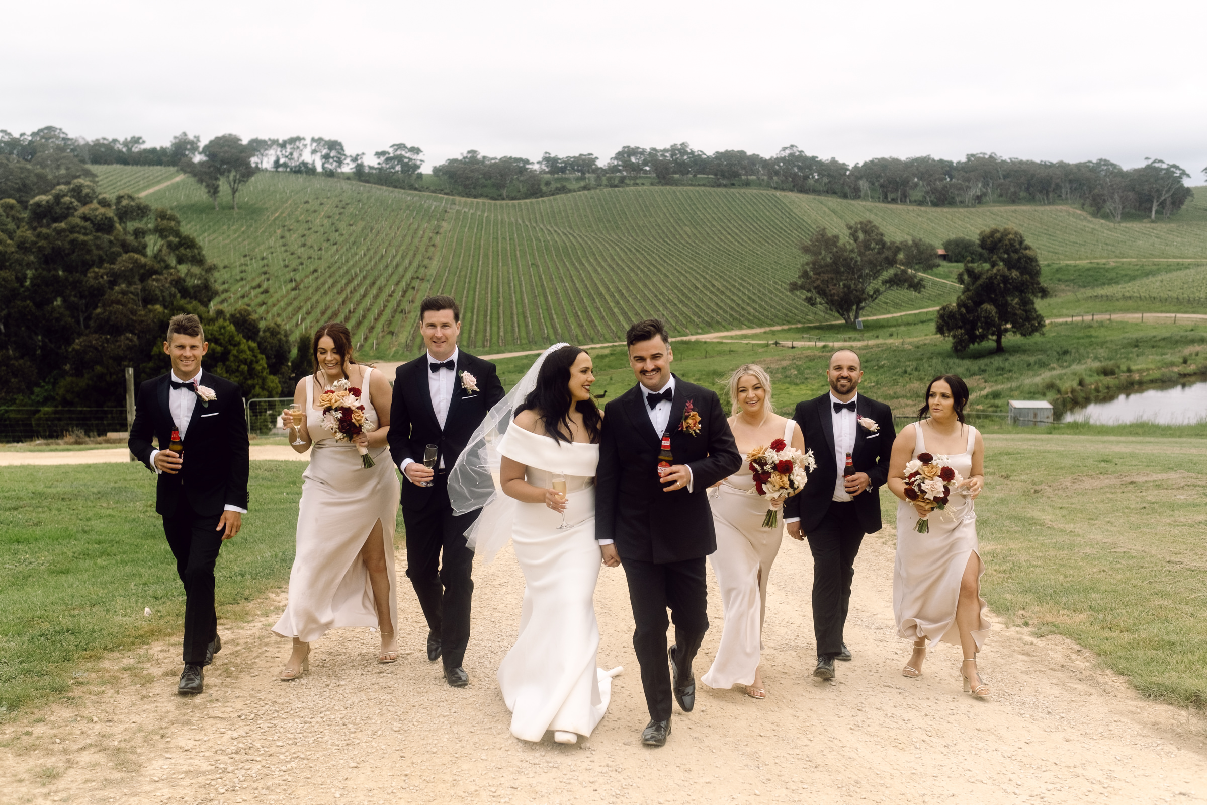 a bridal party walking towards the camera with the rolling views of the Adelaide Hills behind them