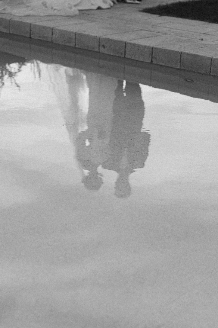 A reflection of a bride and groom in the pool at Amastuola in Puglia, Italy