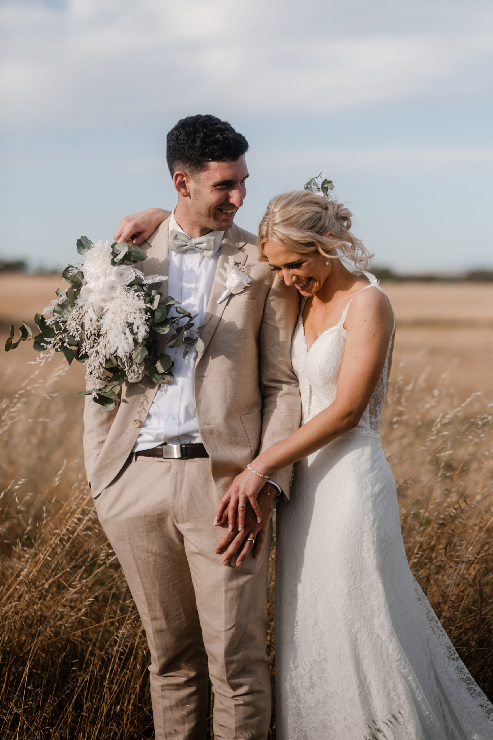 a bride and groom stand side-by-side, holding hands with the Strathalbyn fields in the background