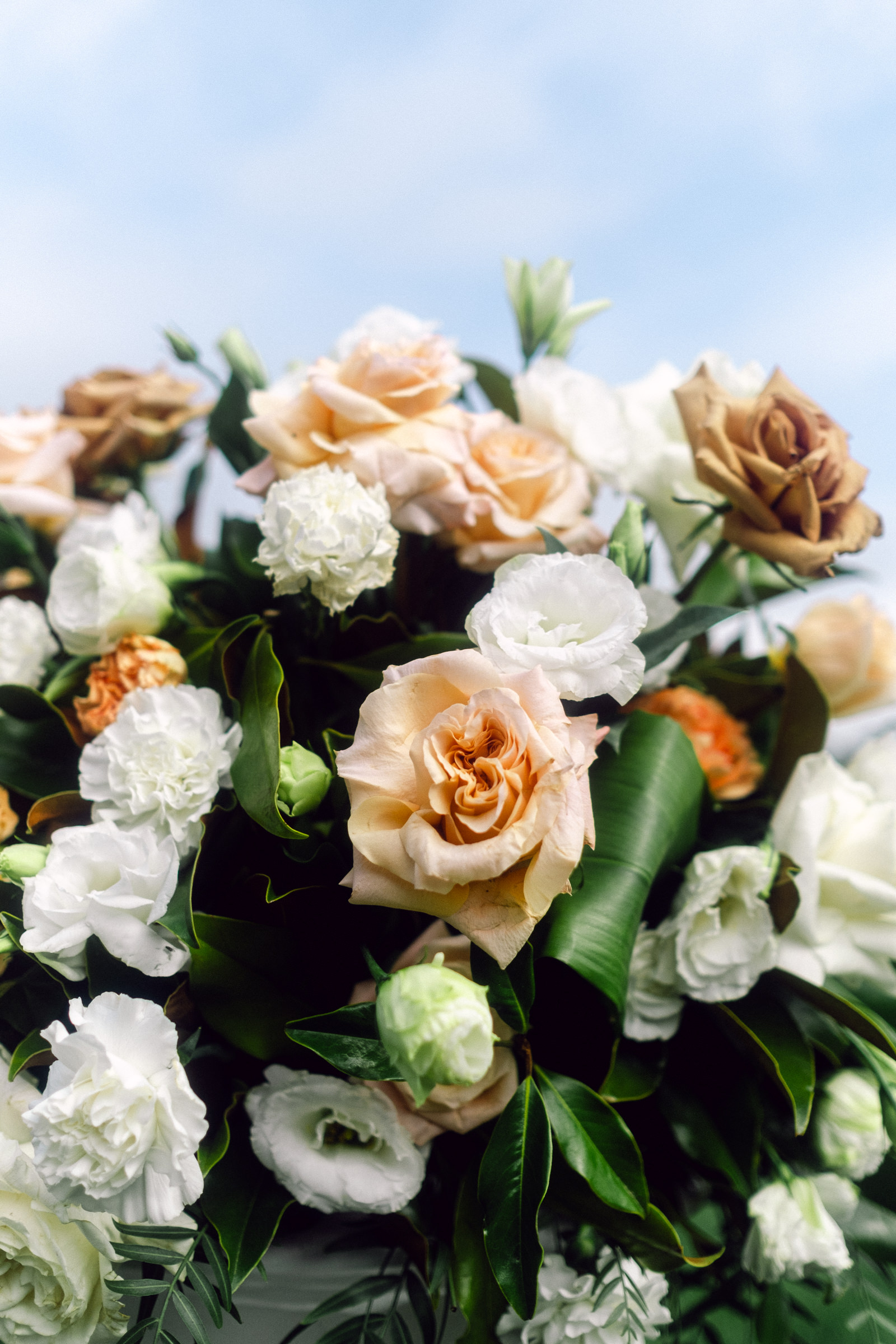 a peach and white floral arrangement with blue sky in the background