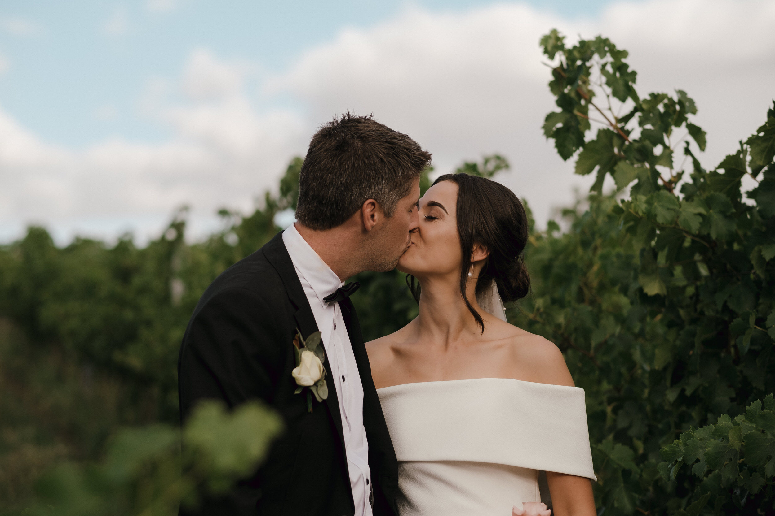 a bride and groom share a kiss in the vines of Howard's Vineyard