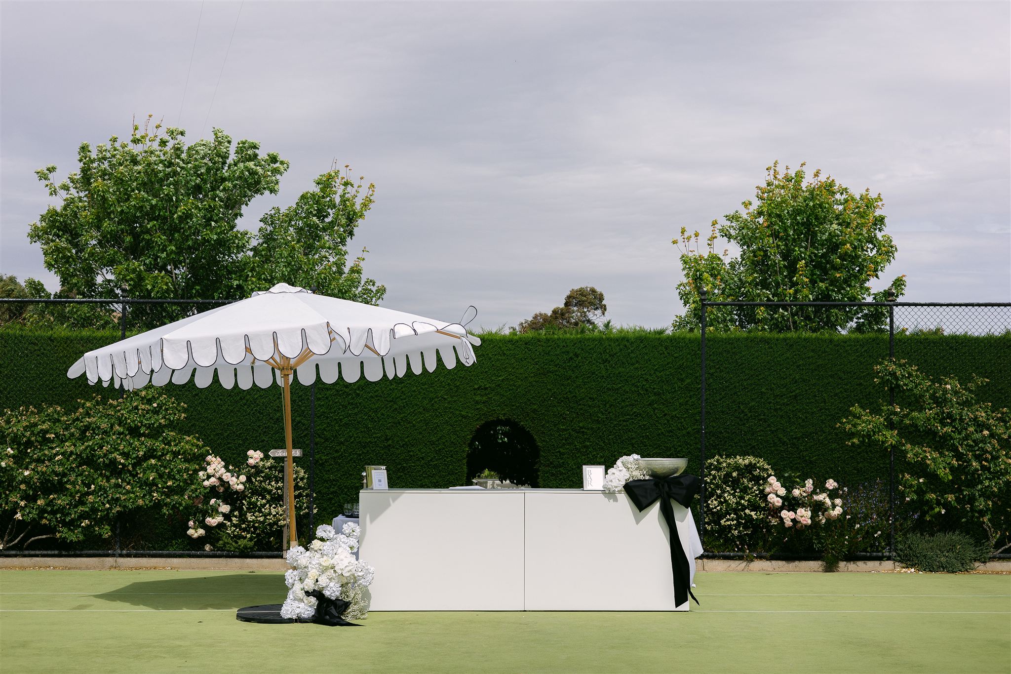 Elegant cocktail hour styling with white umbrella and florals against manicured hedgerows at Mandalay House and Garden, South Australia