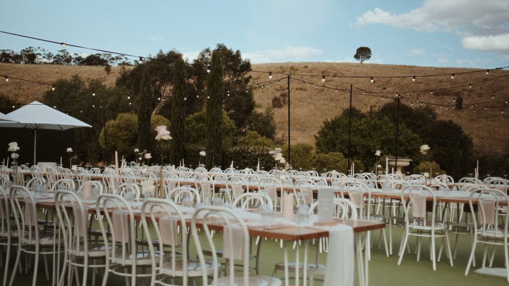 an open air wedding reception set up on a tennis court overlooking the rolling beige fields surrounding Mandalay House and Garden