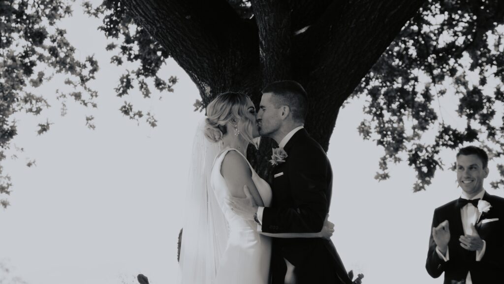 a bride and groom share their first kiss as husband and wife under the tree at Howard Vineyard