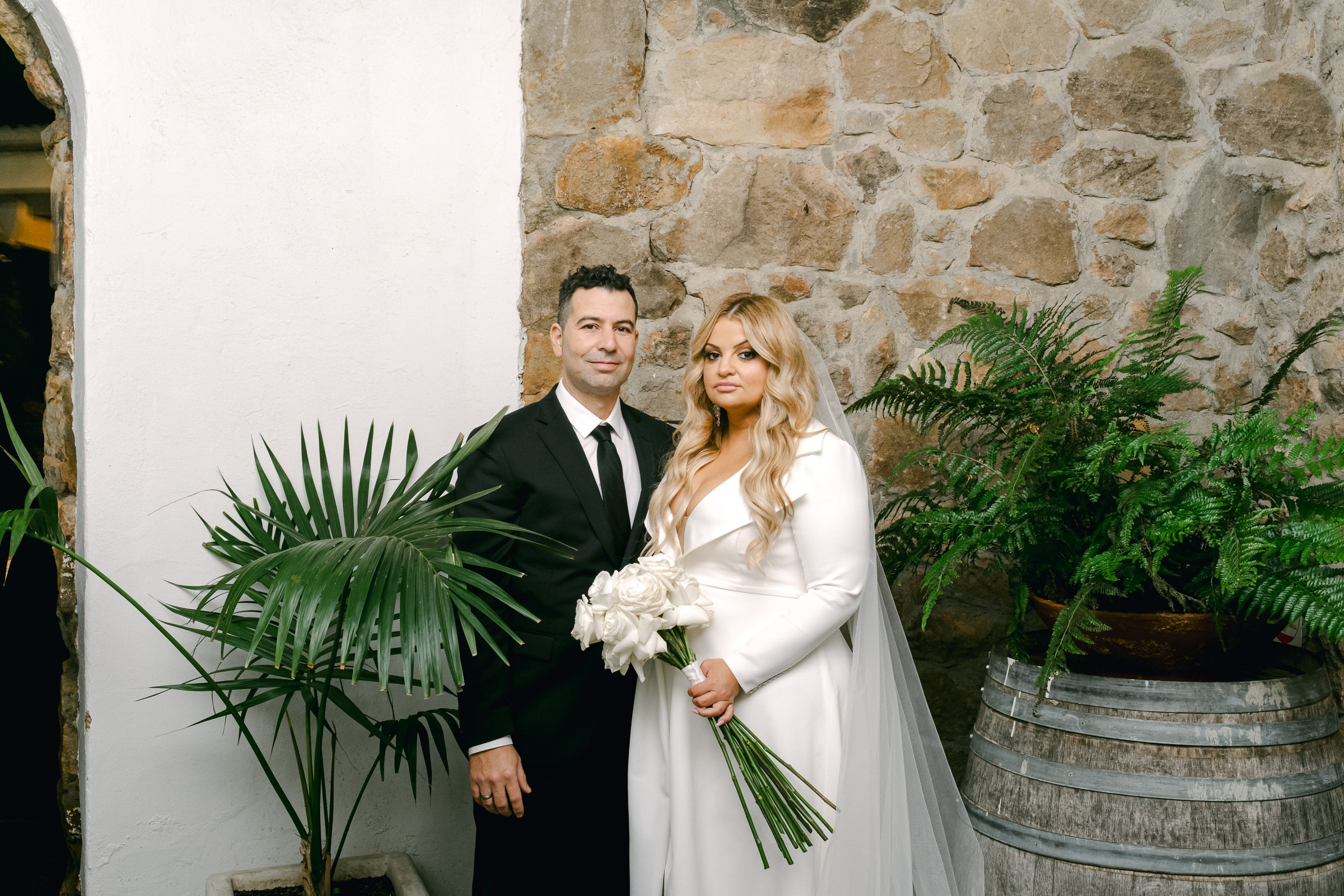 a bride and groom stand in a stone alcove of The Manor Basket Range