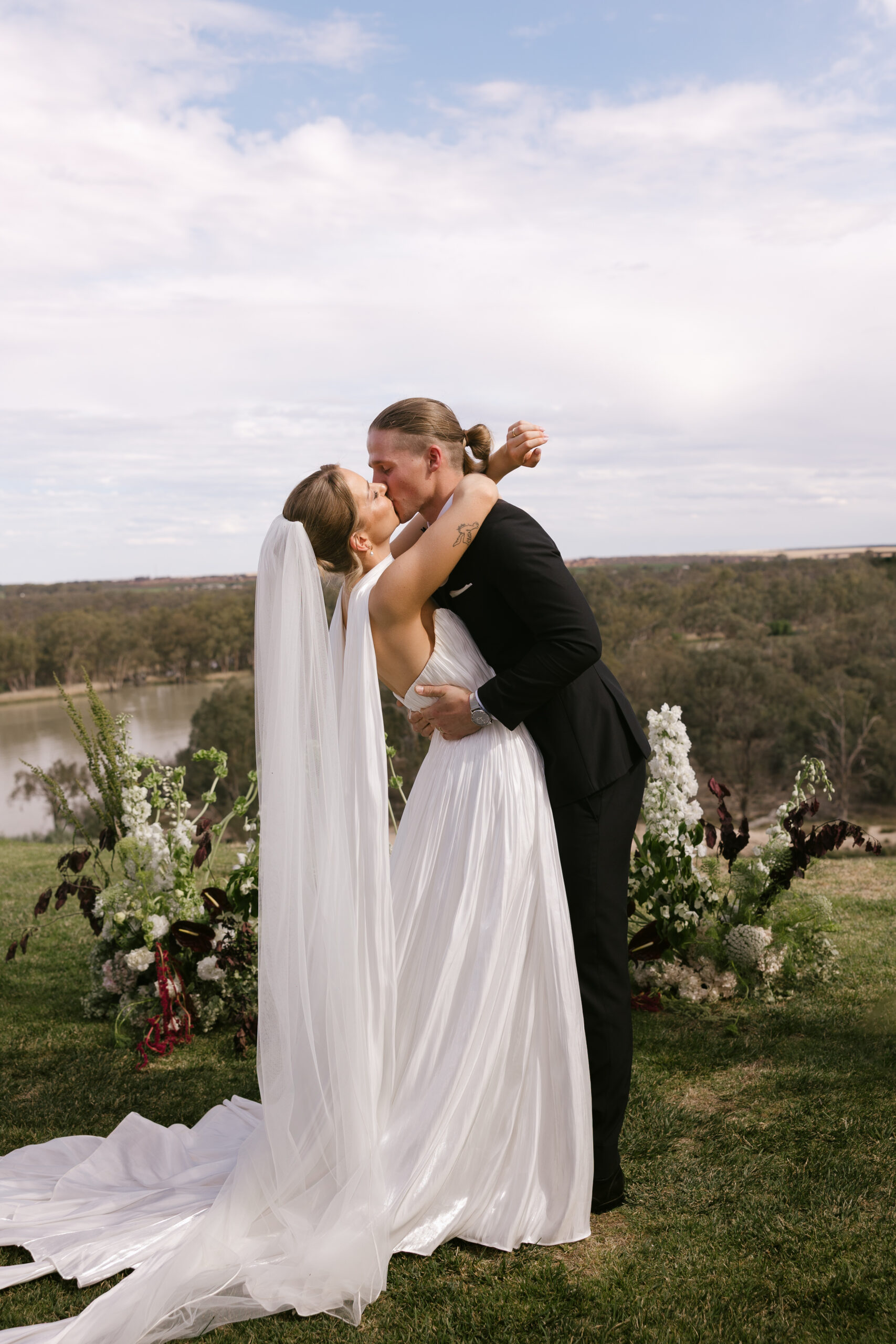 Bride and groom share their first kiss overlooking the cliffs at The River Vista in the Riverland, South Australia, during an elegant outdoor ceremony.