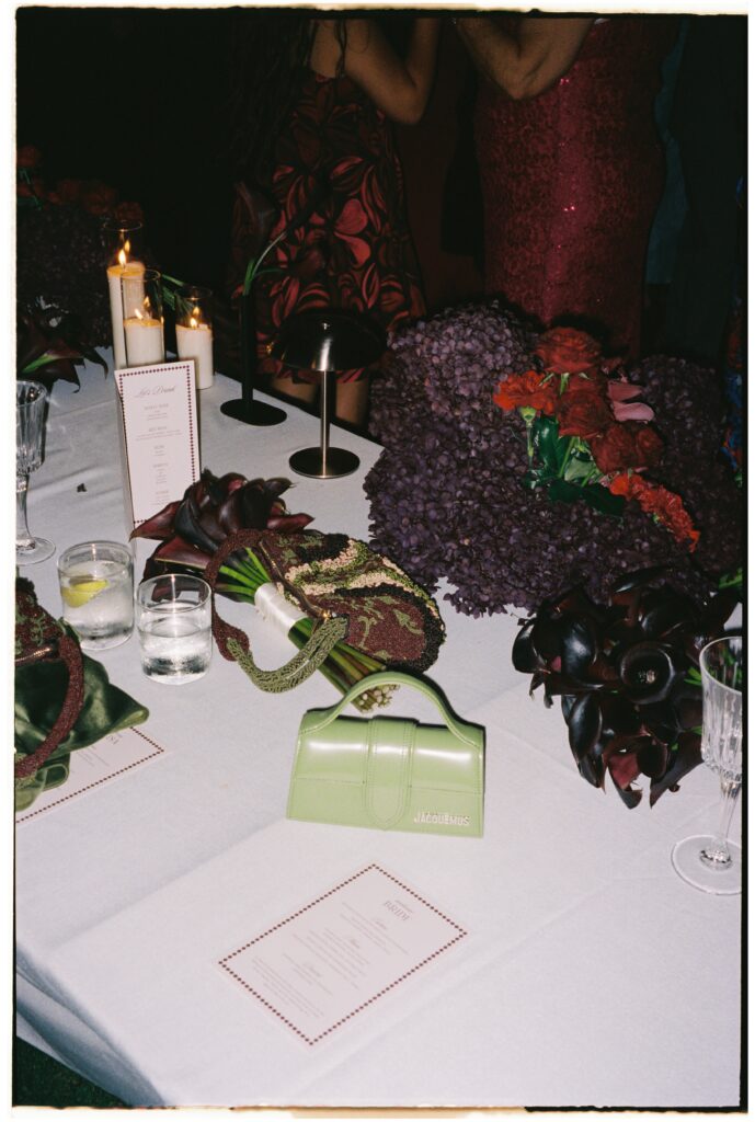 35mm film wedding photography, candlelit reception table with dark florals and Jacquemus bag detail, Evelina Katarzyński
