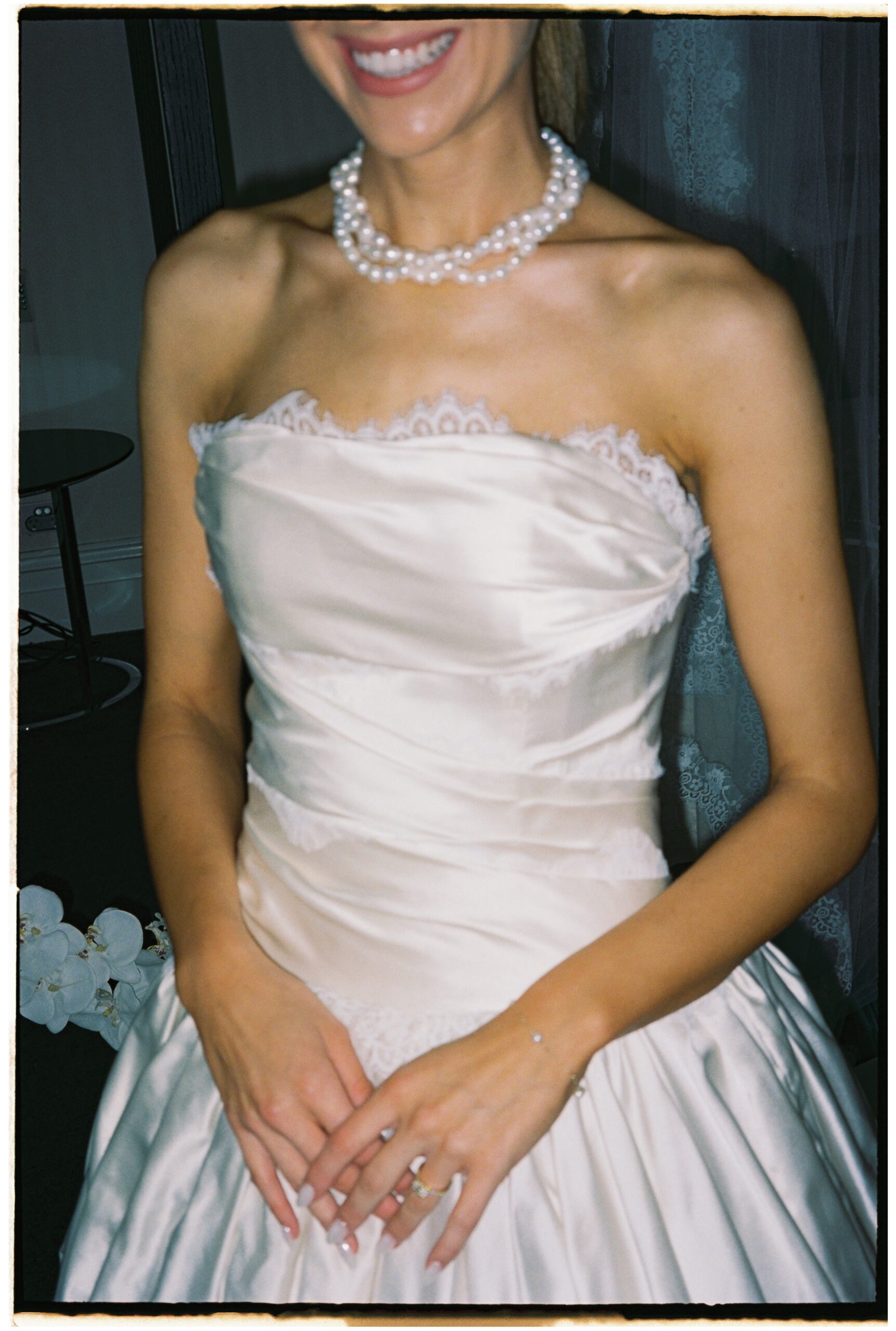 35mm wedding photography, close up of bride in strapless lace gown with hands folded, smiling wth a pearl necklace, Evelina Katarzyński