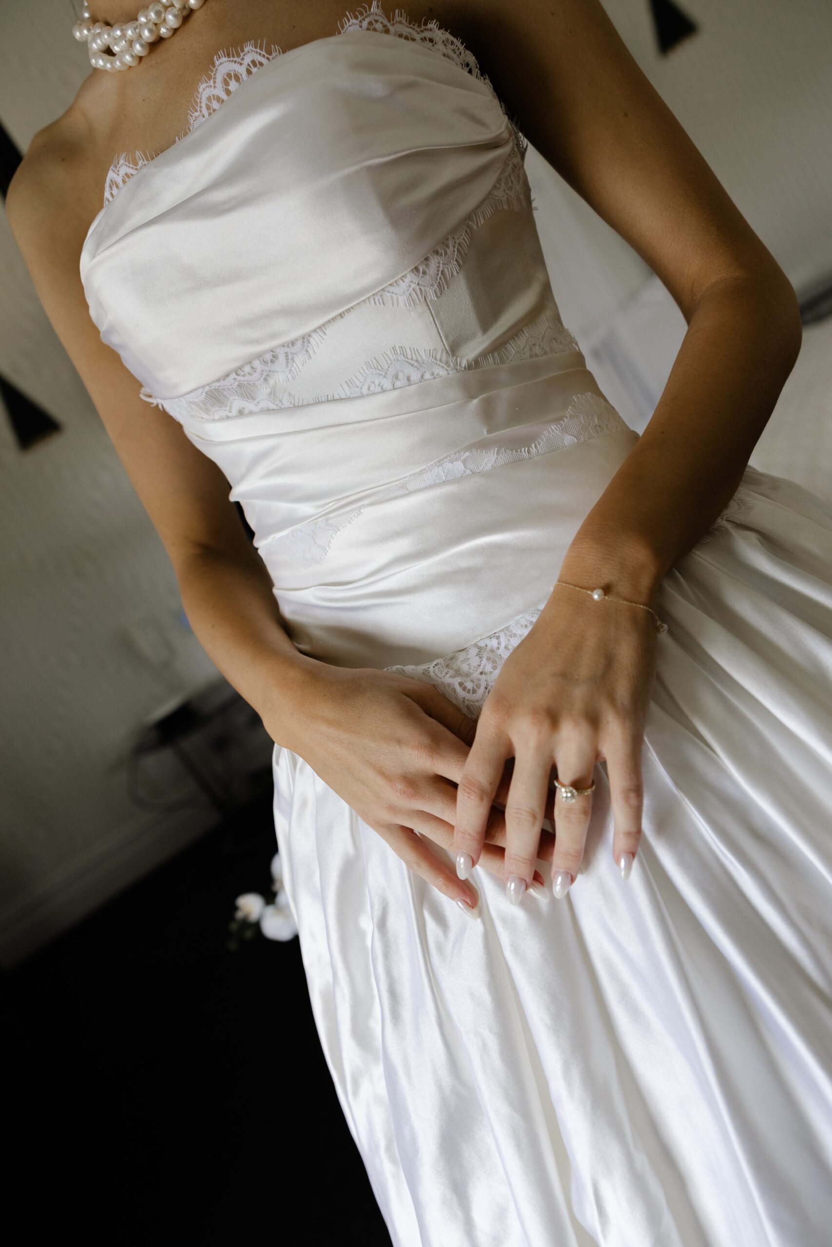 digital wedding photography, close up of bride in strapless lace gown with hands folded, sharp detail on fabric and ring, Evelina Katarzyński