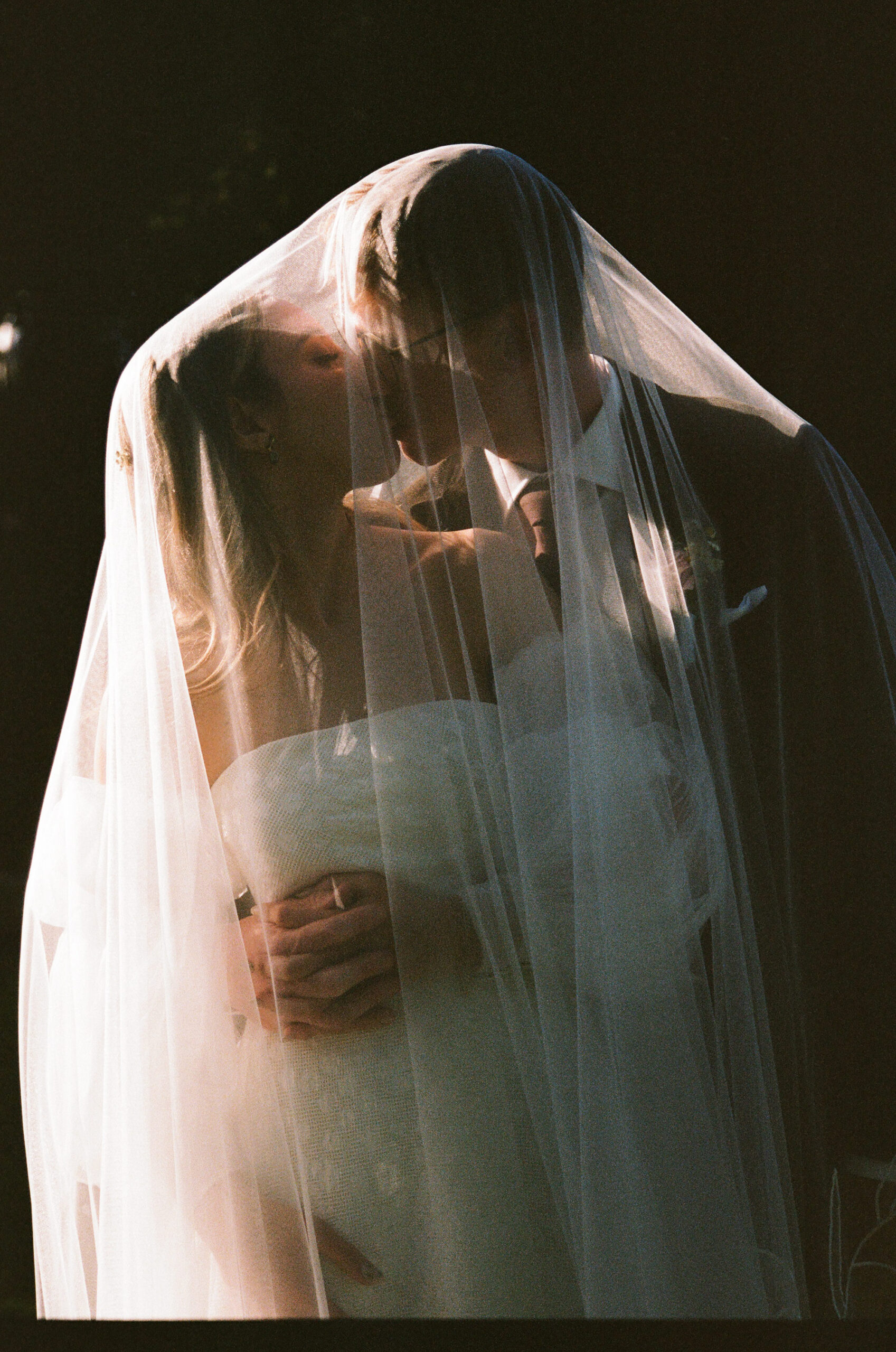 35mm film wedding photography, couple kissing under veil, Evelina Katarzyński