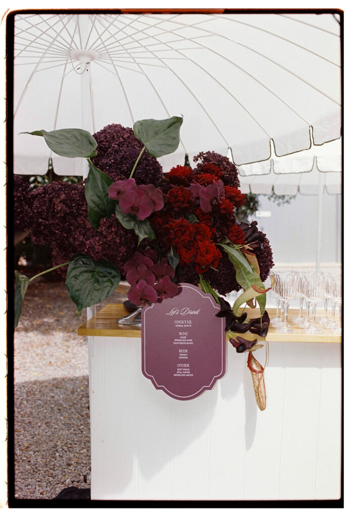 35mm film wedding photography, outdoor ceremony setup with burgundy florals and marquee, Evelina Katarzyński
