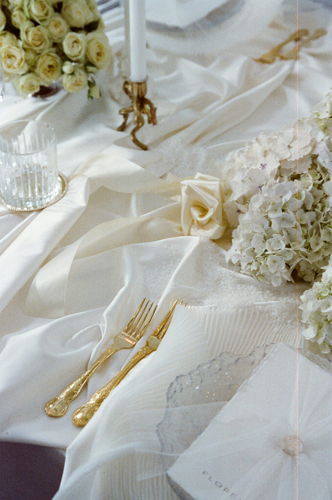 35mm film wedding photography, styled place setting with gold cutlery white roses and lace detail, Evelina Katarzyński
