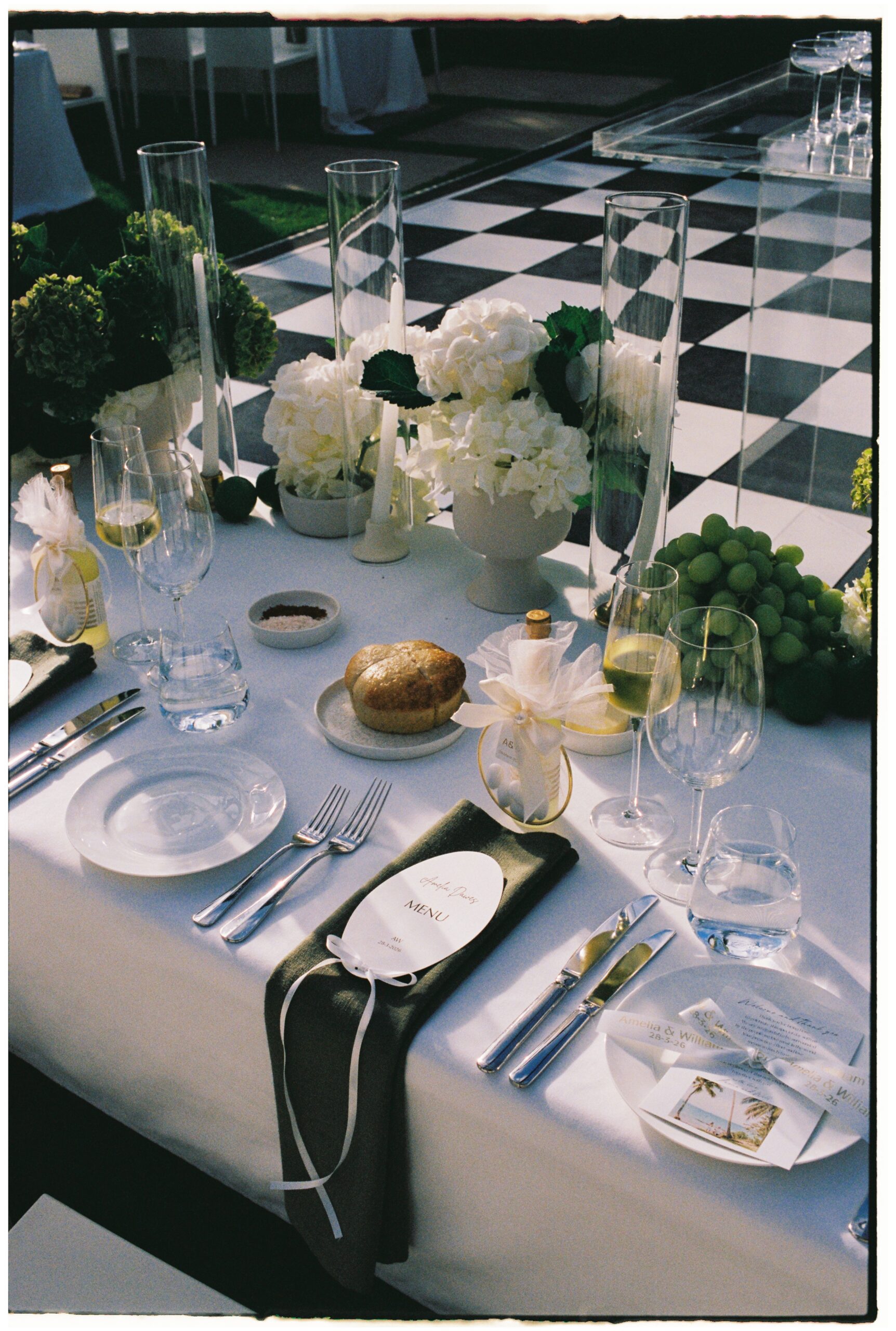 35mm film wedding photography, reception place setting with white hydrangeas, green grapes and checkered dancefloor, Evelina Katarzyński