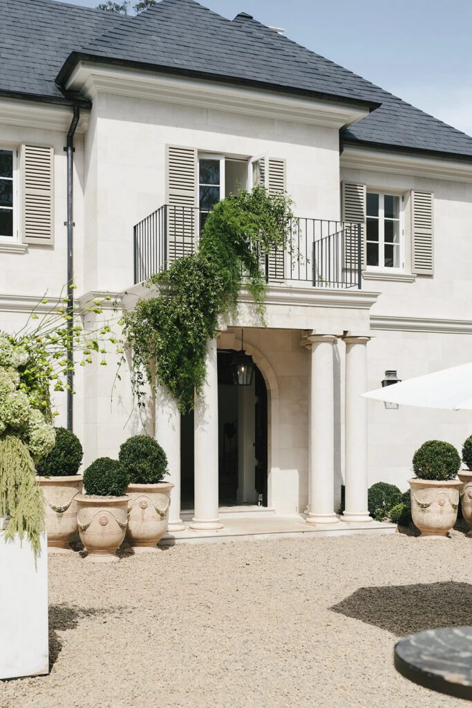 White French chateau style exterior with ivy-covered walls, black shutters and manicured topiary at La Gemme Estate wedding venue, Bowral NSW Australia