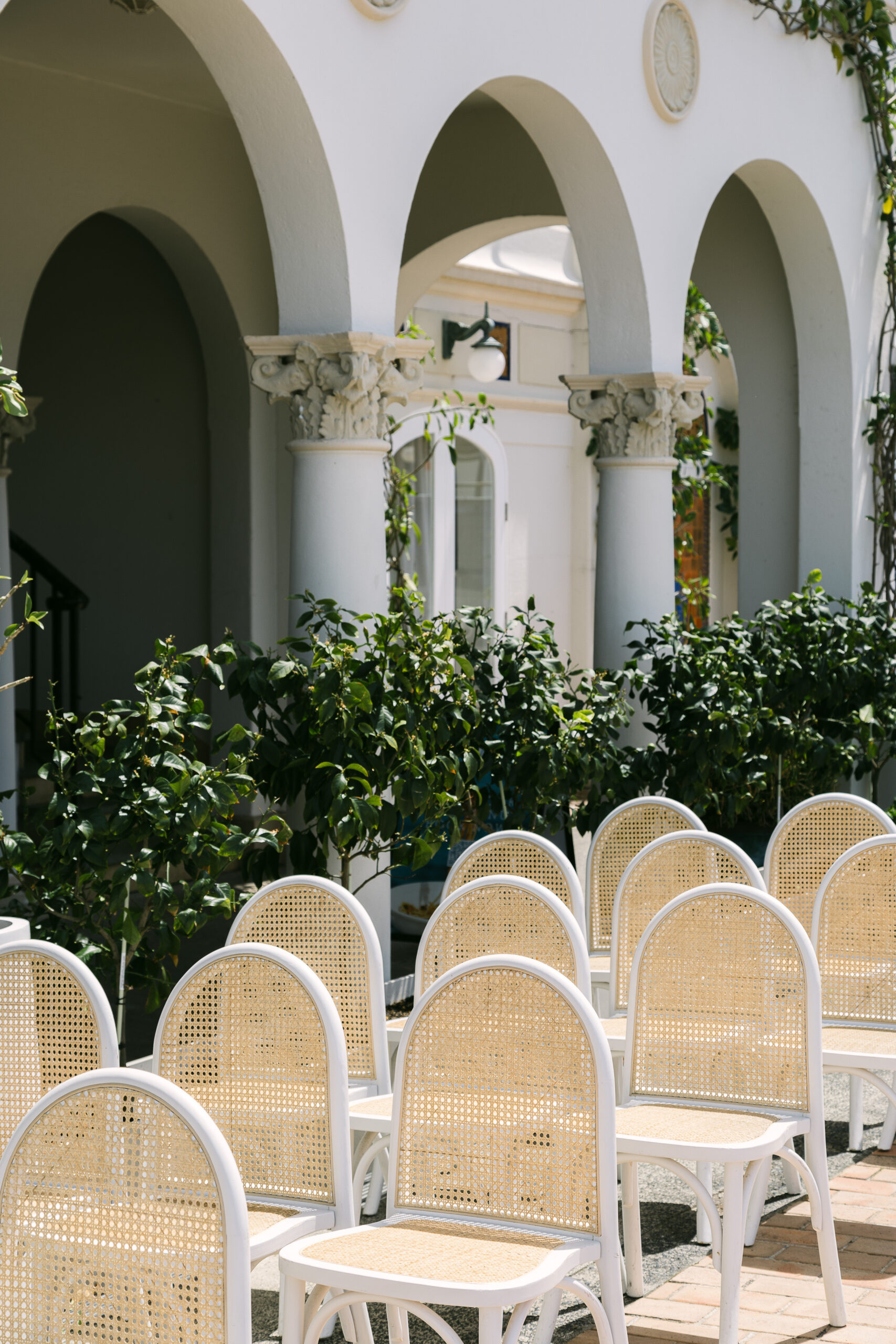 Wedding ceremony chairs arranged in the outdoor courtyard at Manly Pavilion with floral arch and colonial architecture
