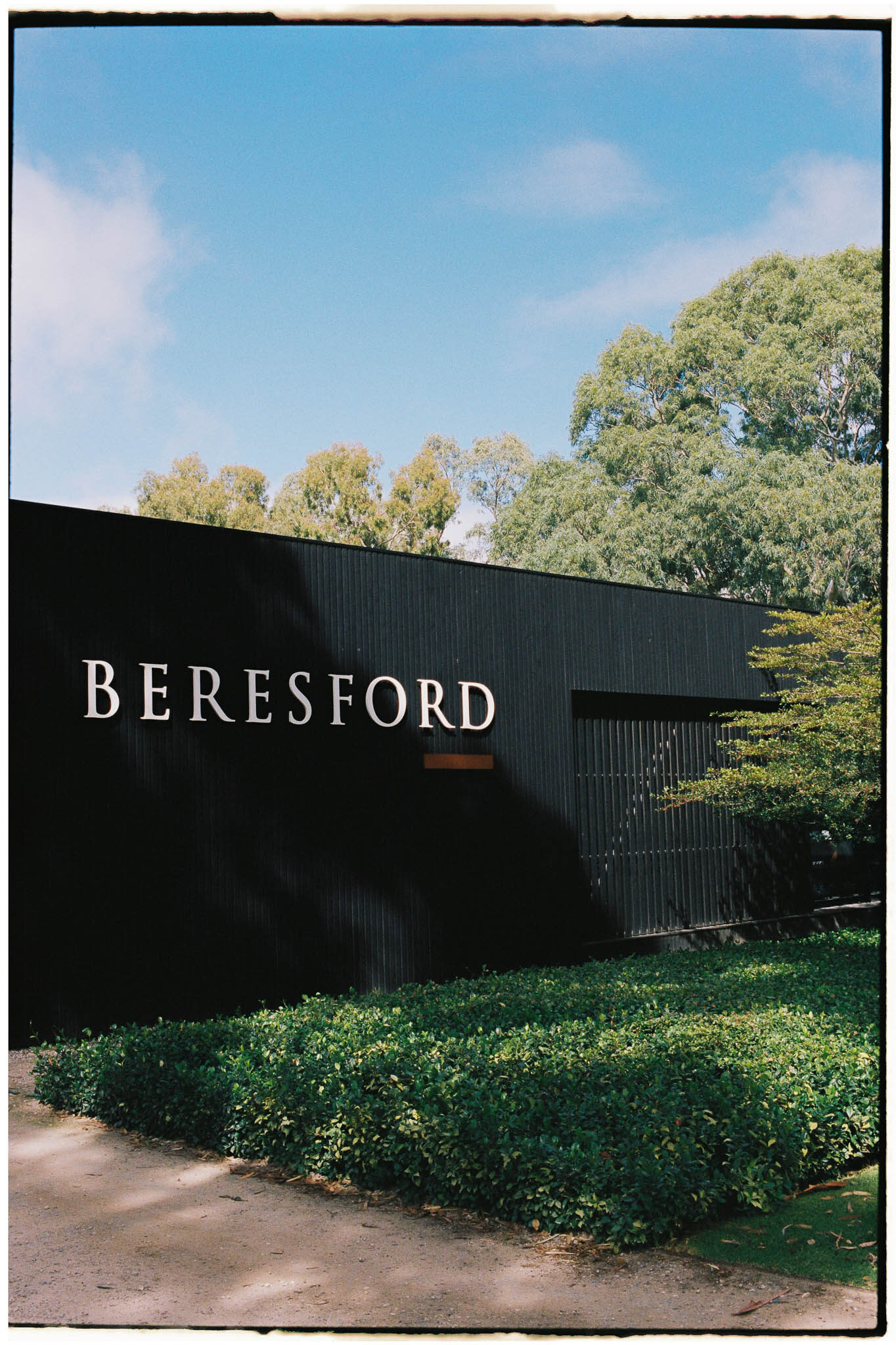 Alt text: Beresford Estate entrance signage in McLaren Vale, framed by clipped hedging on 35mm film.
