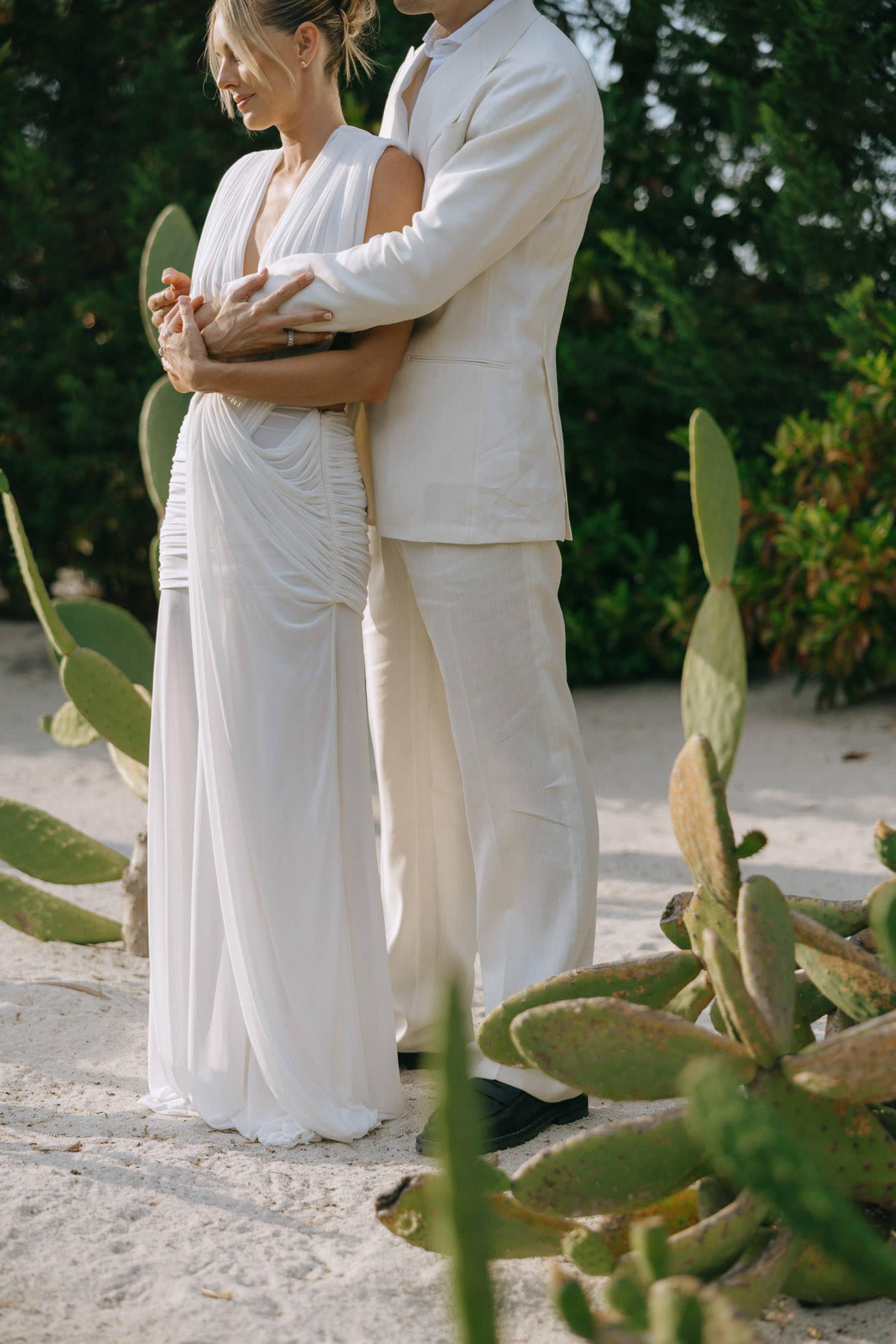 Couple embracing among cactus garden at Quinta da Comporta wedding welcome dinner.