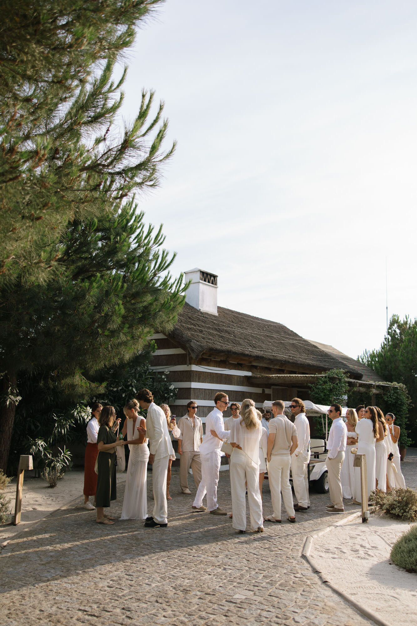Guests gathering on cobblestone path in white attire at Quinta da Comporta wedding welcome dinner